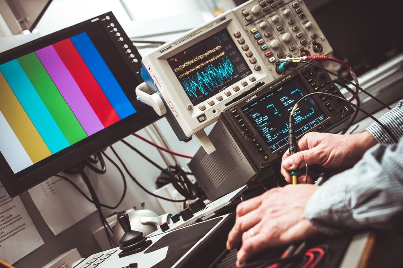 Close-up hands operating precision analog oscilloscope and measurement equipment