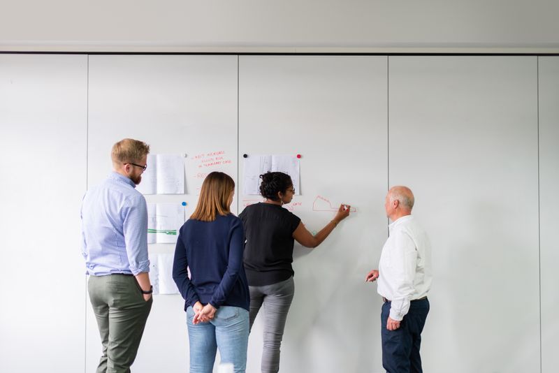 Engineering leadership discussing architectural milestones at a whiteboard